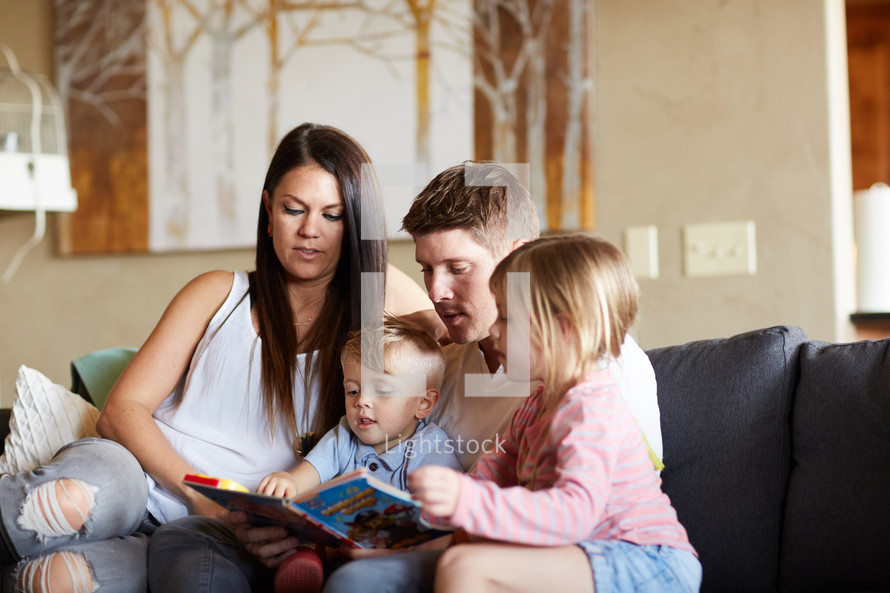 a family reading a children's book on the couch 