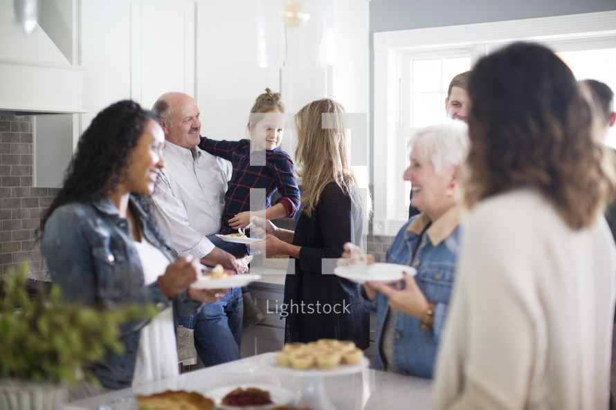family gathered in the kitchen to get dessert at Thanksgiving 