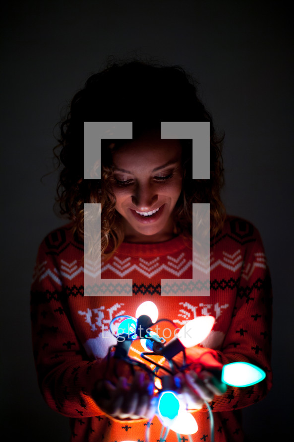 a woman holding glowing Christmas lights 
