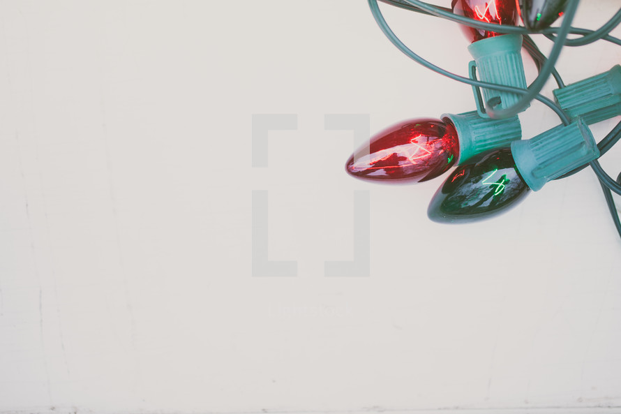 Tangle of red and green Christmas lights on a white background.