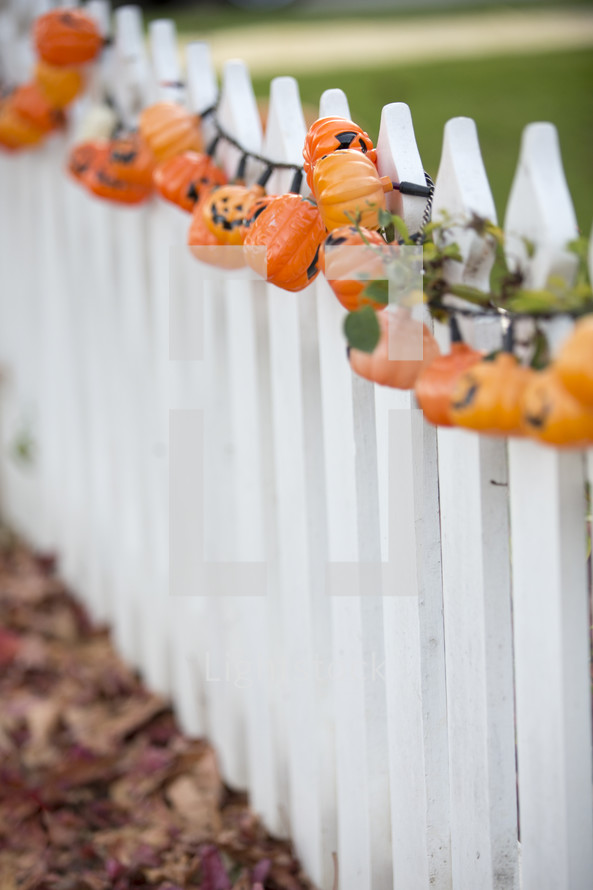 pumpkin lights on a fence 
