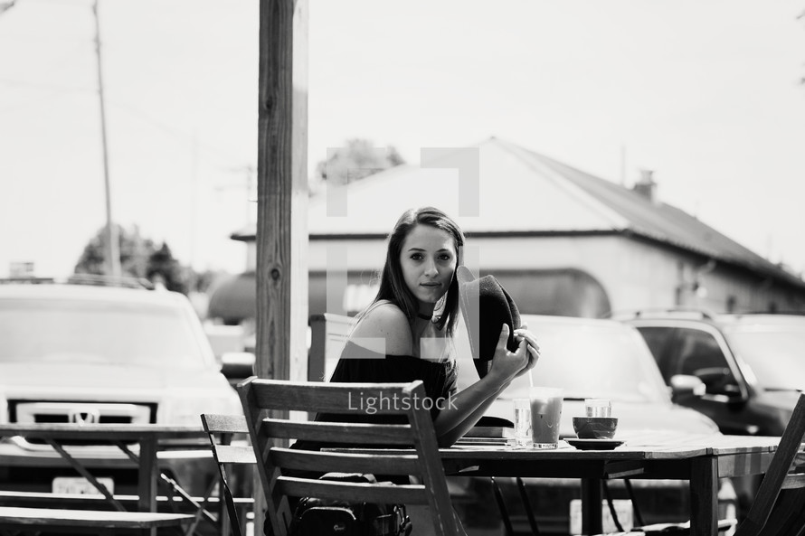 woman sitting and iced coffee and cappuccino on a wooden table outdoors 