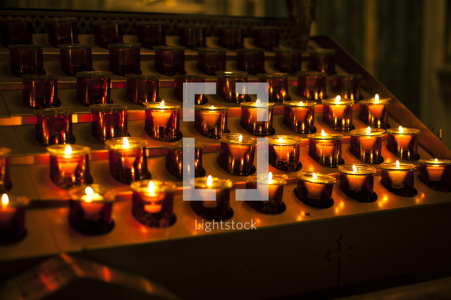 Rows of lit votive candles.