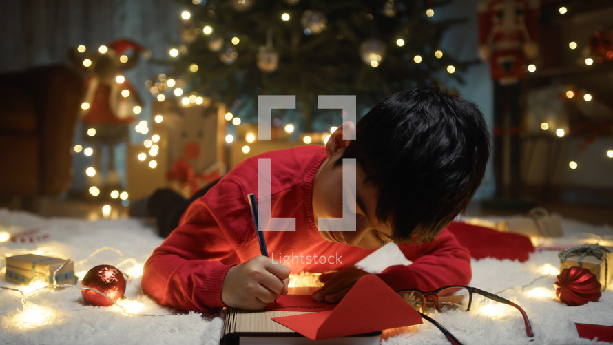 Kid writing Christmas letter for santa Claus 