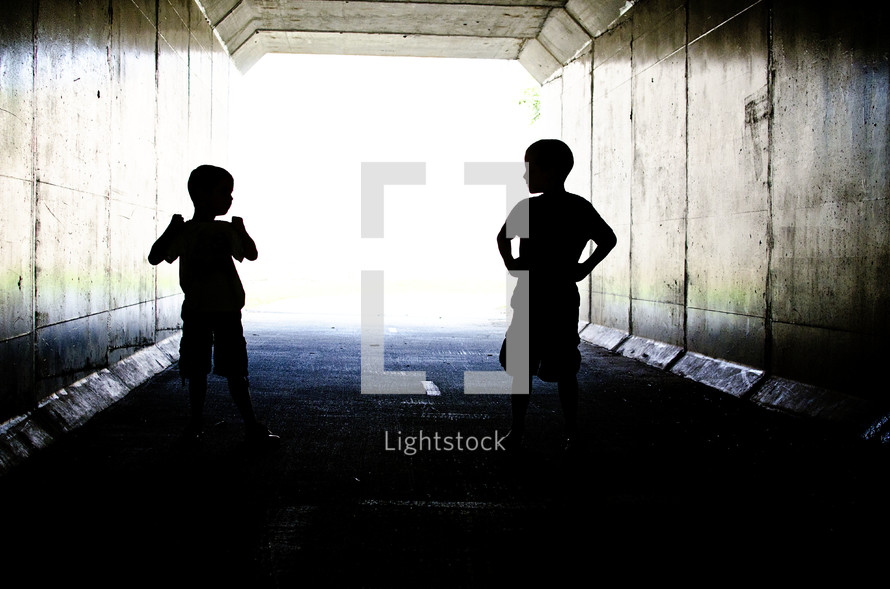 Silhouette of children playing in a tunnel.