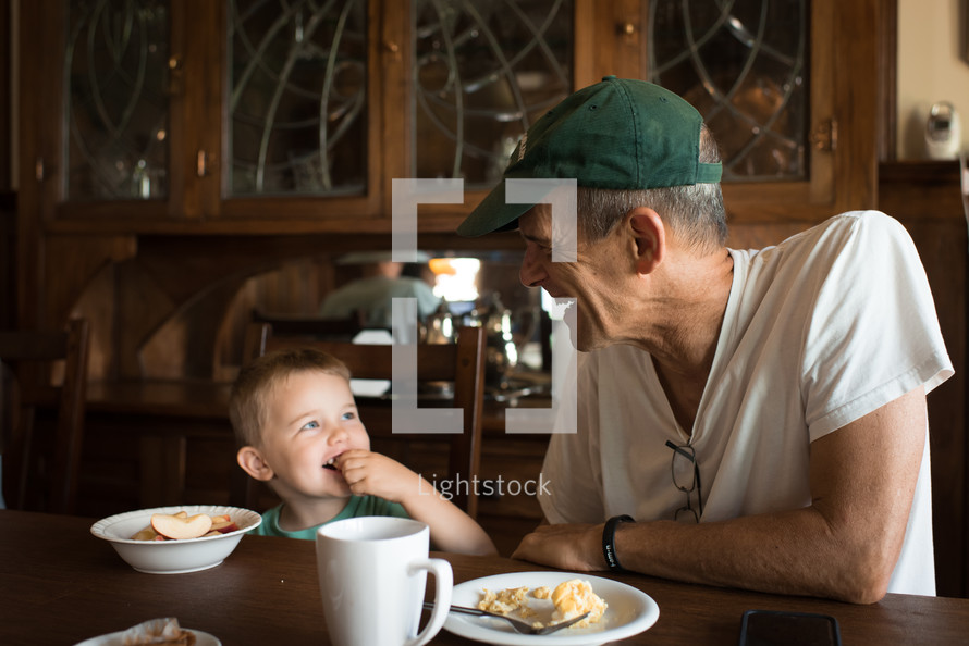 a grandfather and grandson eating a snack together 