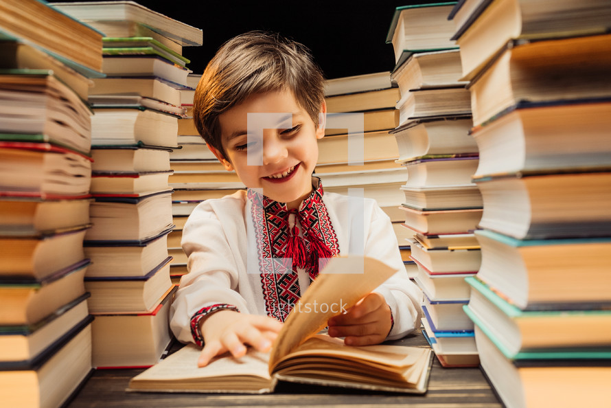 Handsome little ukrainian child flips through book pages in library. Elementary school boy enjoying reading in bookshop or bookstore