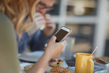 a woman checking her cellphone over breakfast 