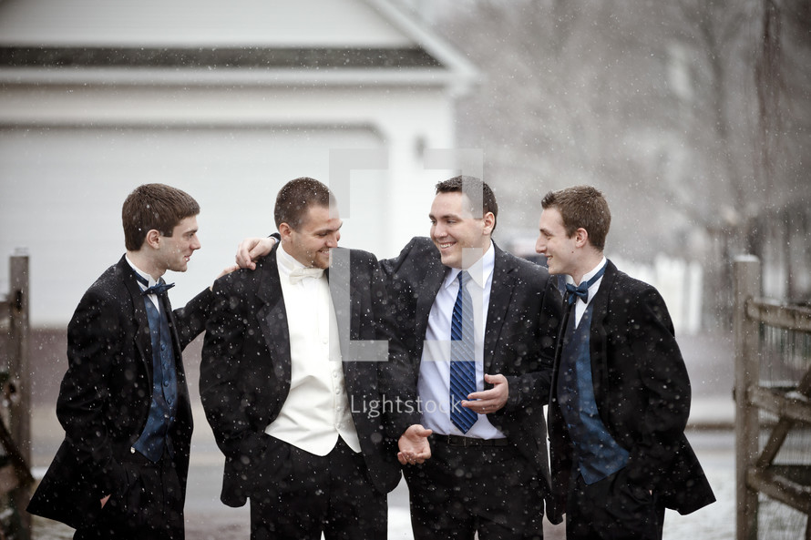 groom and groomsmen in falling snow