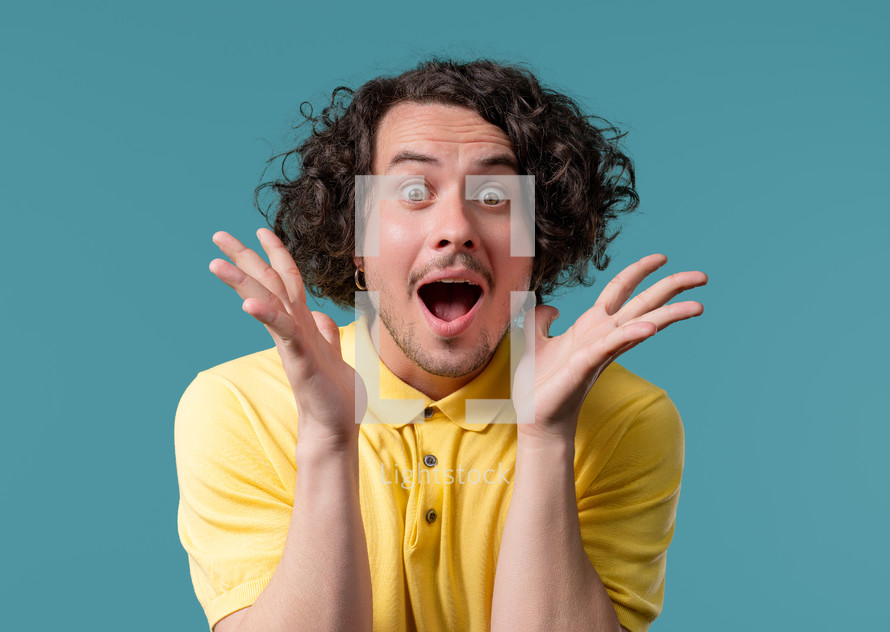 Shocked curly haired man glad, he screaming WOW. Impressed guy trying to get attention. Concept of summer sale, profitable offer. Excited happy on blue background. High quality