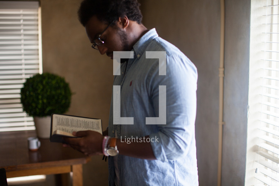 An African American man standing reading a Bible 