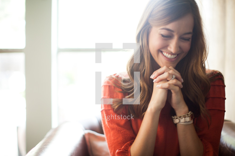 a smiling woman with praying hands 