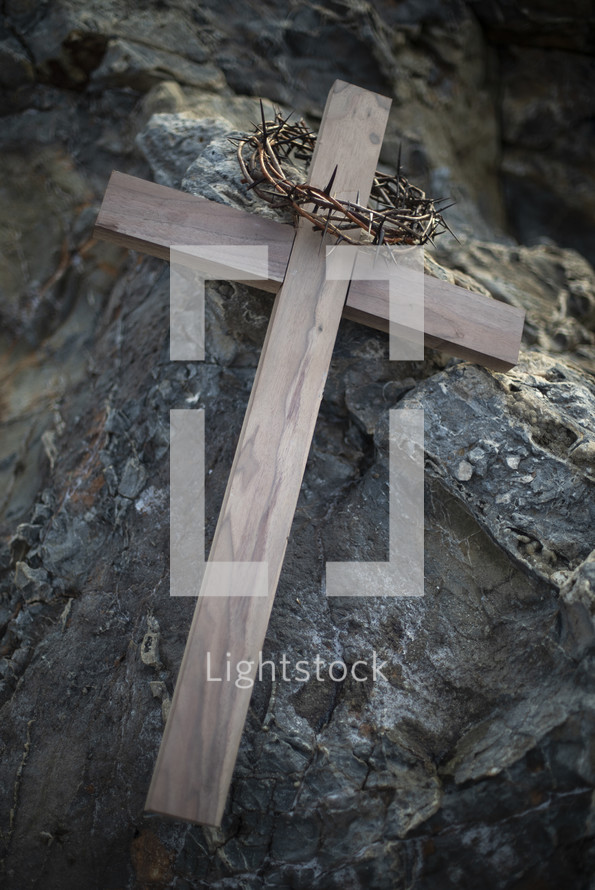 crown of thorns and wooden cross on a rock 