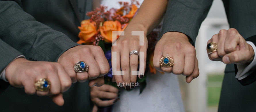groom, groomsmen, and bride showing off rings 
