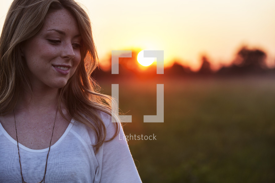 young woman standing outdoors at sunset 