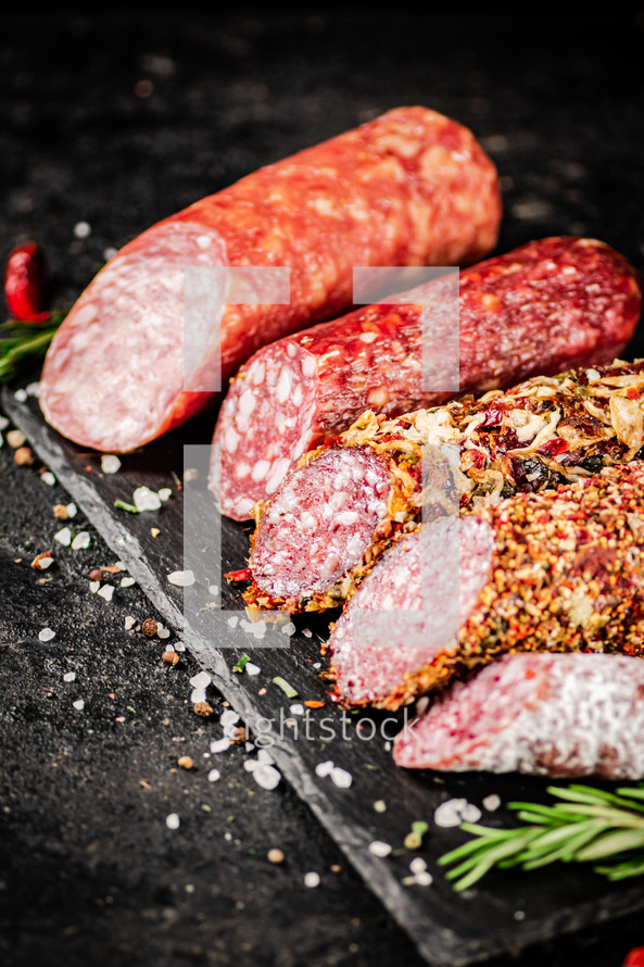 Assortment of various aromatic salami sausages. Against a dark background. High quality photo