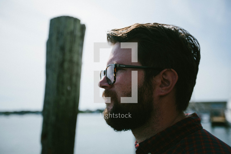 a man with a beard looking out at a harbor 