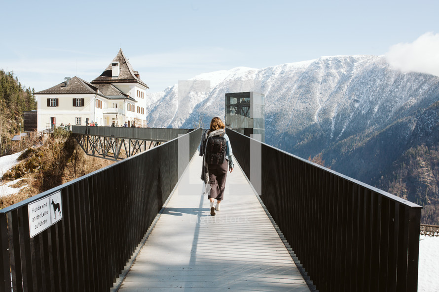 person walking across a bridge in a mountain town in Austria 