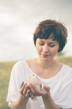 Woman holding a dove outside.