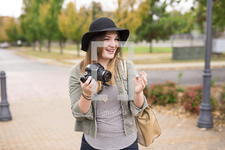 a woman on campus holding a camera 