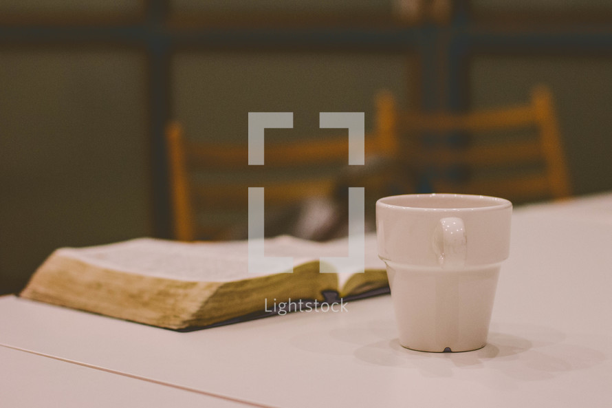 open Bible on a table and coffee mug 