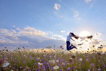 teenage girl jumping in a summer field