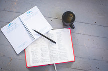 a opened Bible and coffee cup on an outdoor table 