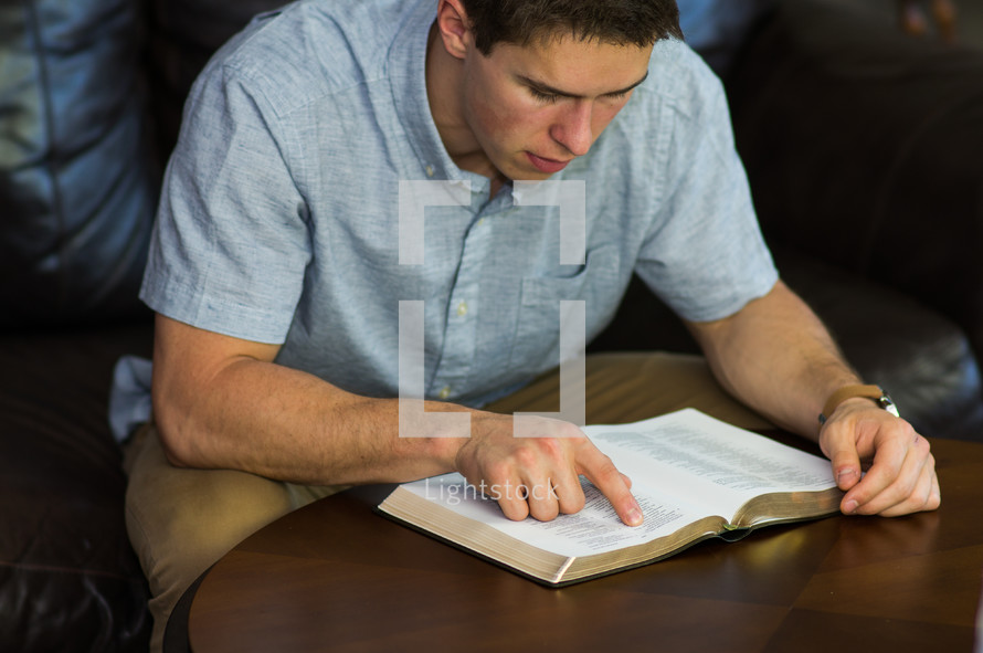 a man pointing to scripture while reading a Bible 