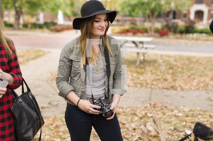 a woman on campus holding a camera 