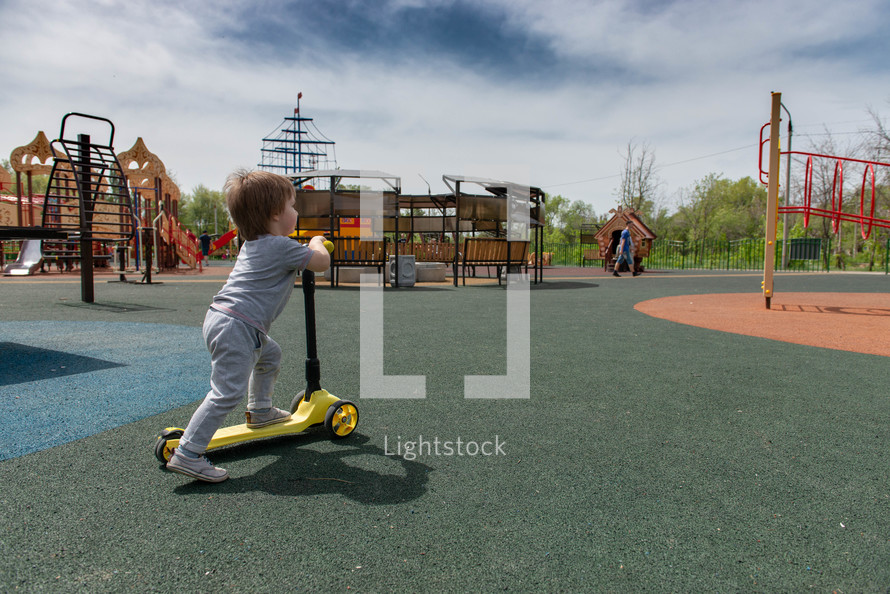 toddler with a scooter on a playground 