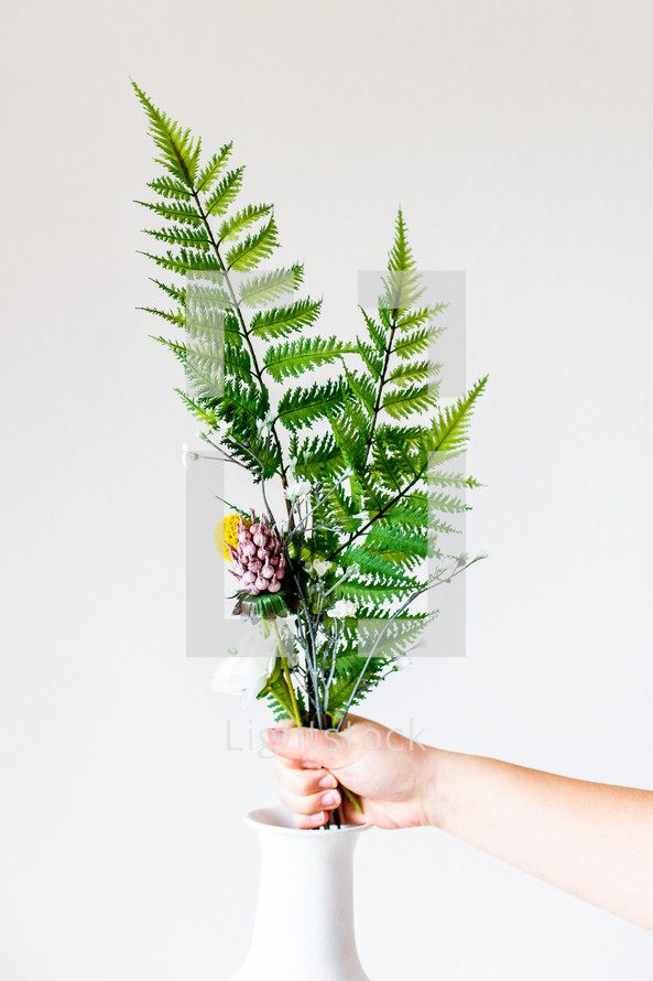 placing ferns and flowers in a vase 