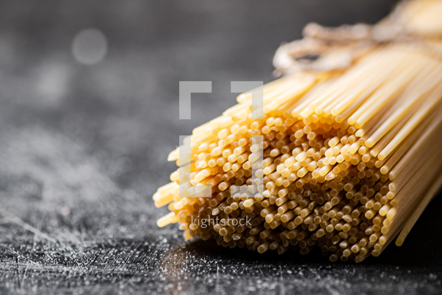 A pile of spaghetti dry on the table. Against a dark background. High quality photo