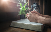 praying hands over an open Bible 