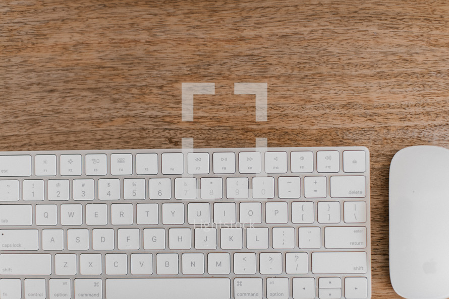 computer keyboard and mouse on a wooden desk 