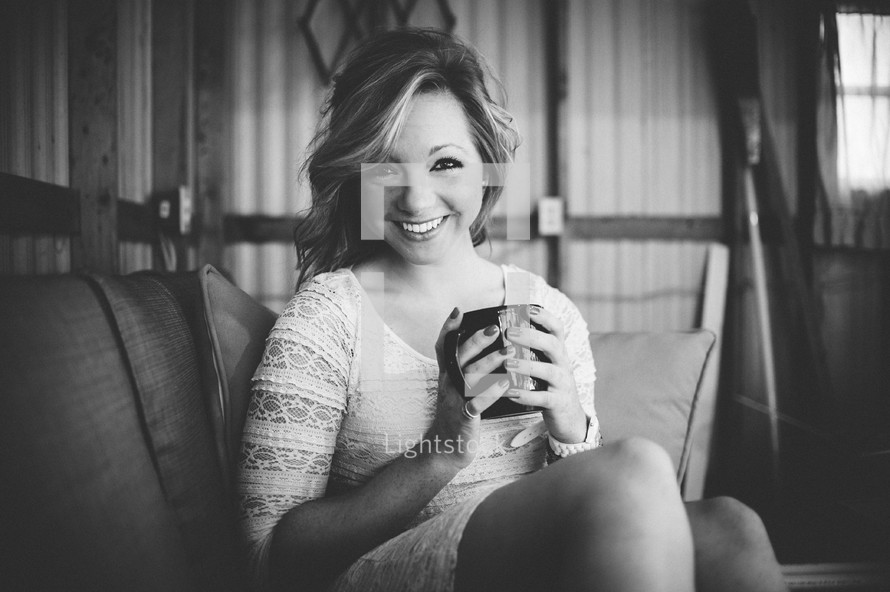 A smiling woman sitting and holding a coffee mug.