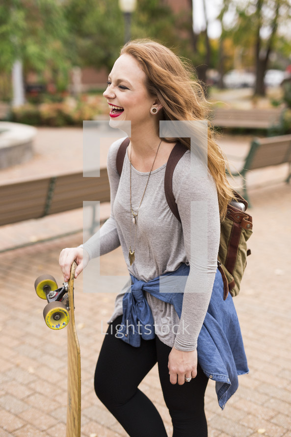 teen girl walking to class carrying a skateboard 