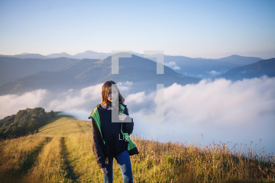 a teen girl walking on a mountaintop 