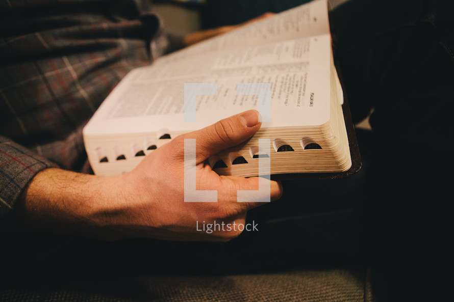 Man's hands holding an open Bible.
