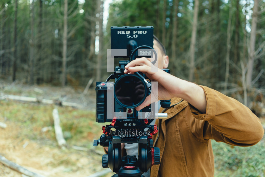 man with a video camera in a forest 