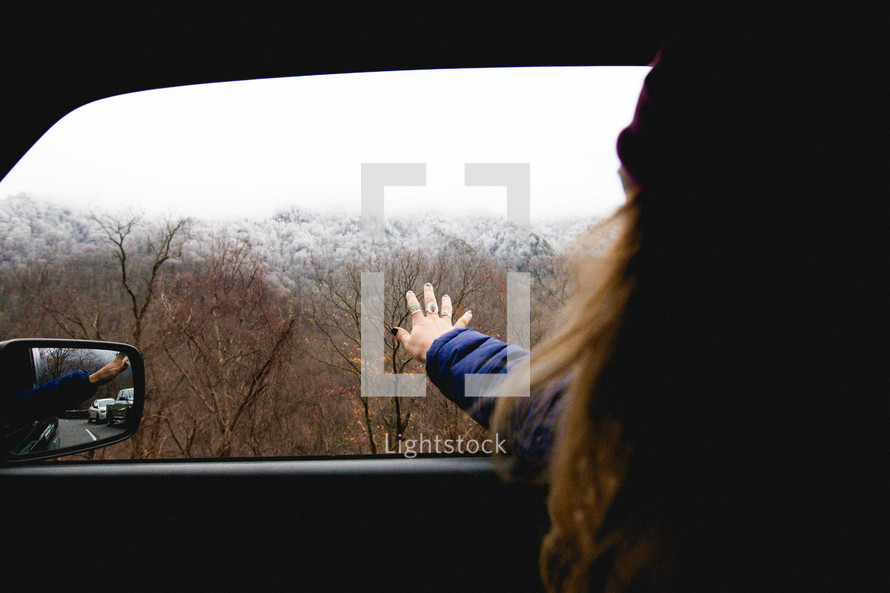 a woman with her hand out a car window 