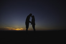 silhouette of a couple kissing at sunset 