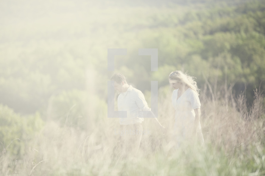 Couple walking together in a field of grass.