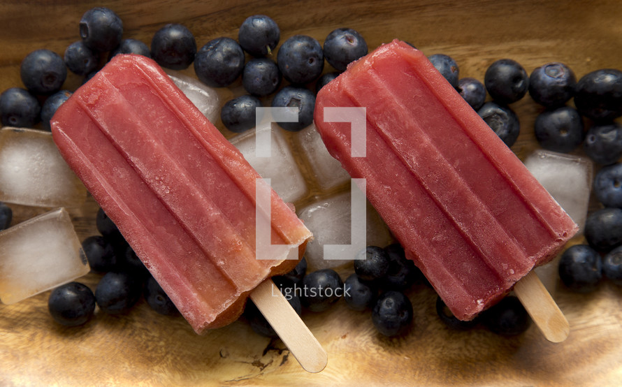 Frozen Homeamde Blueberry Popsicles in a Wooden Bowl