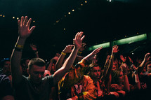 youth in the crowd at a youth rally with raised hands 
