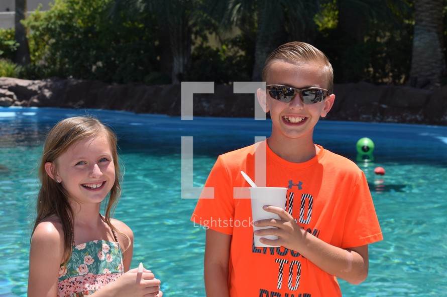 smiling children enjoying a summer day poolside with snow cones 