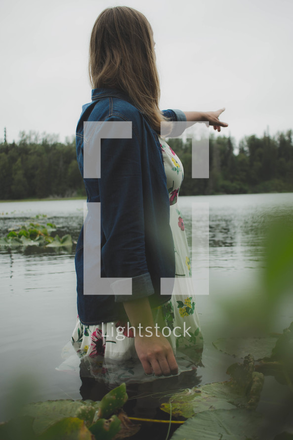woman standing in a lake pointing 