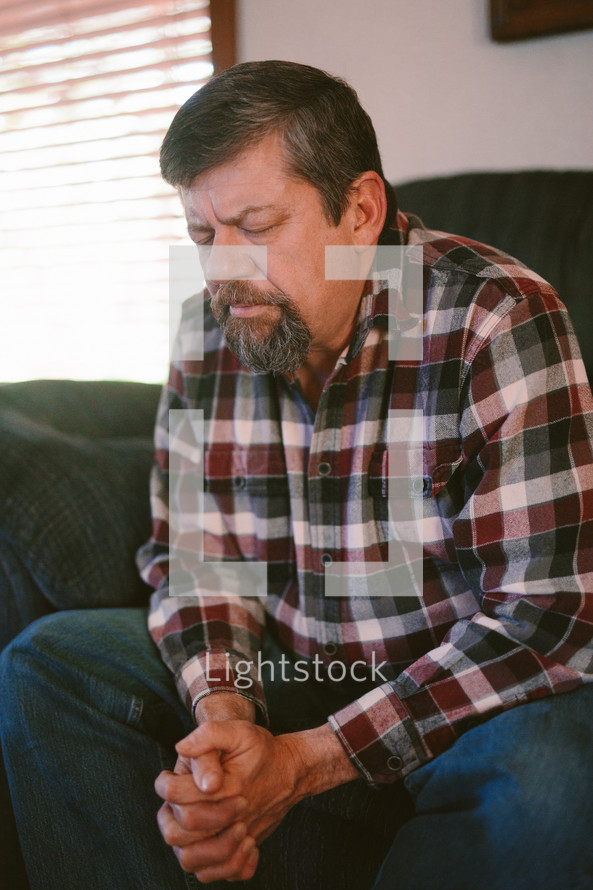 a man praying on a couch 