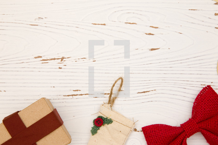 rustic tan Christmas stockings, present, and red bow on white wood background 
