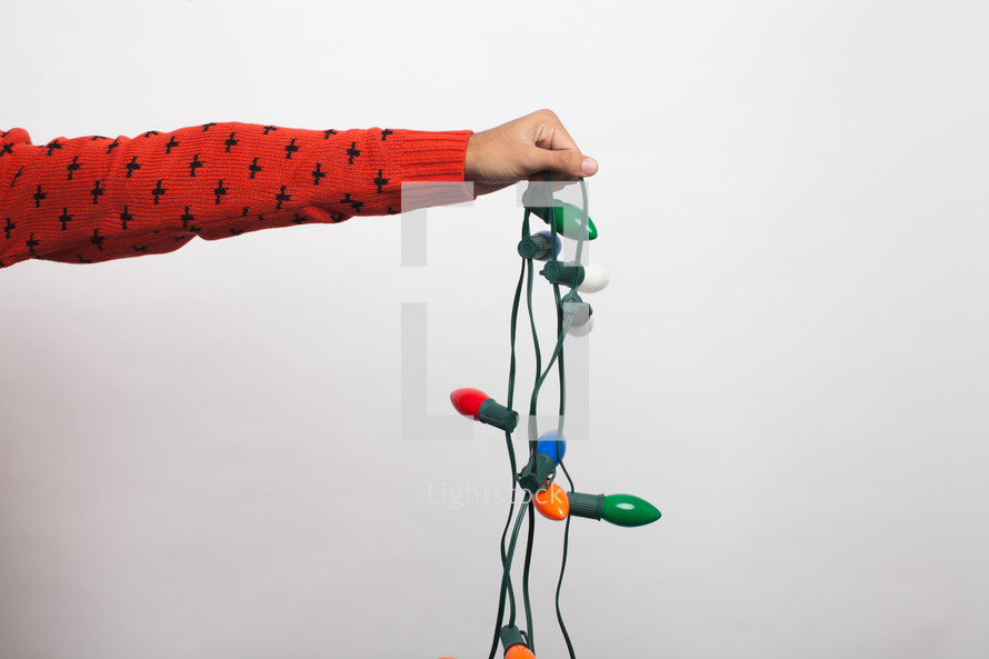 arm holding a strand of Christmas lights 