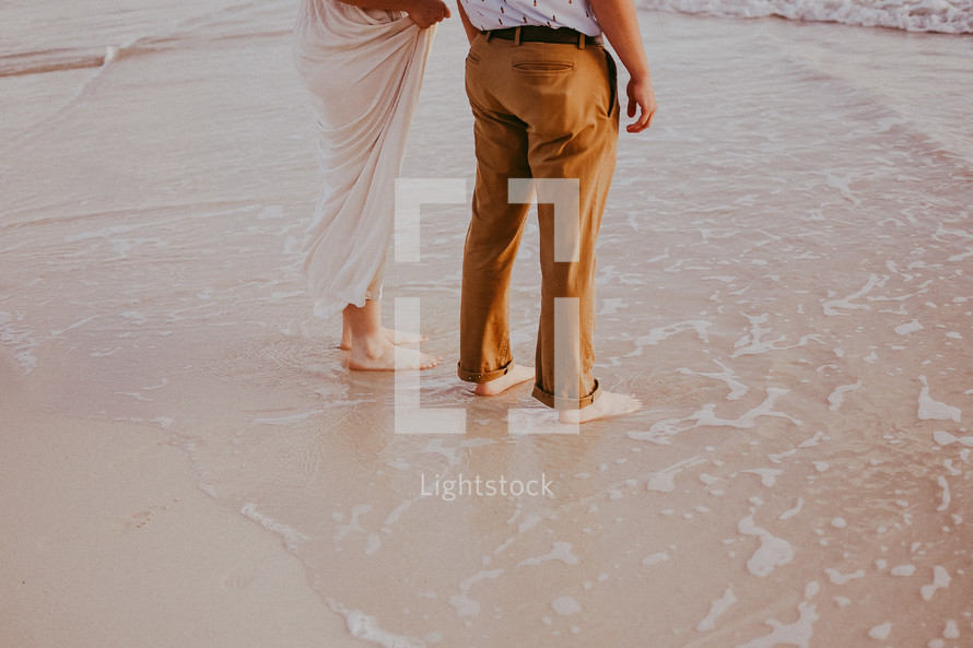 a couple holding hands walking on a beach 